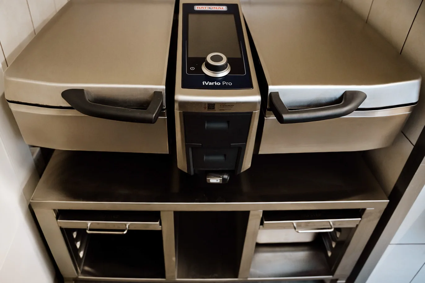 Profesjonalna patelnia elektryczna RATIONAL iVario Pro ze stali nierdzewnej, z panelem sterowania i podwójną komorą roboczą w kuchni gastronomicznej.