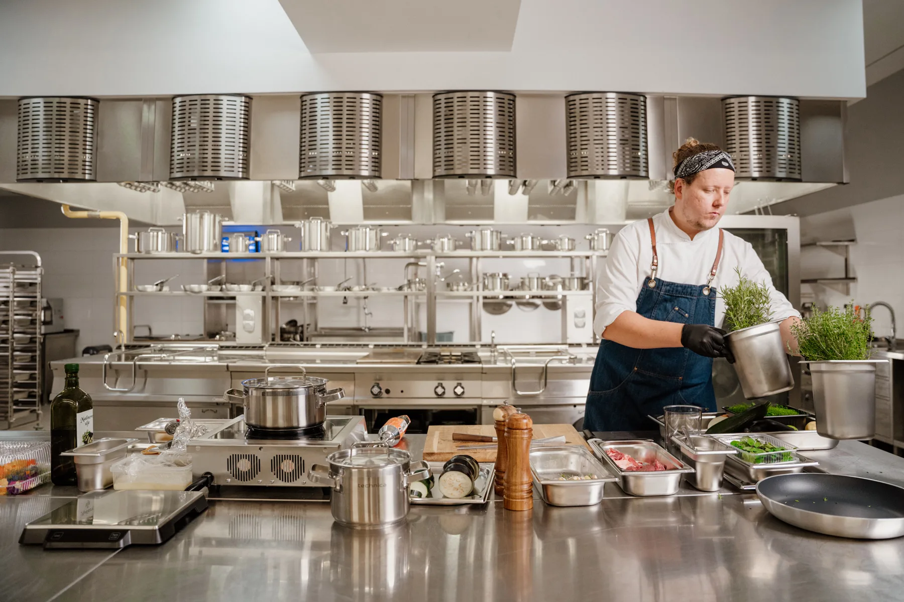 Szef kuchni w profesjonalnej kuchni w otoczeniu sprzętu gastronomicznego.