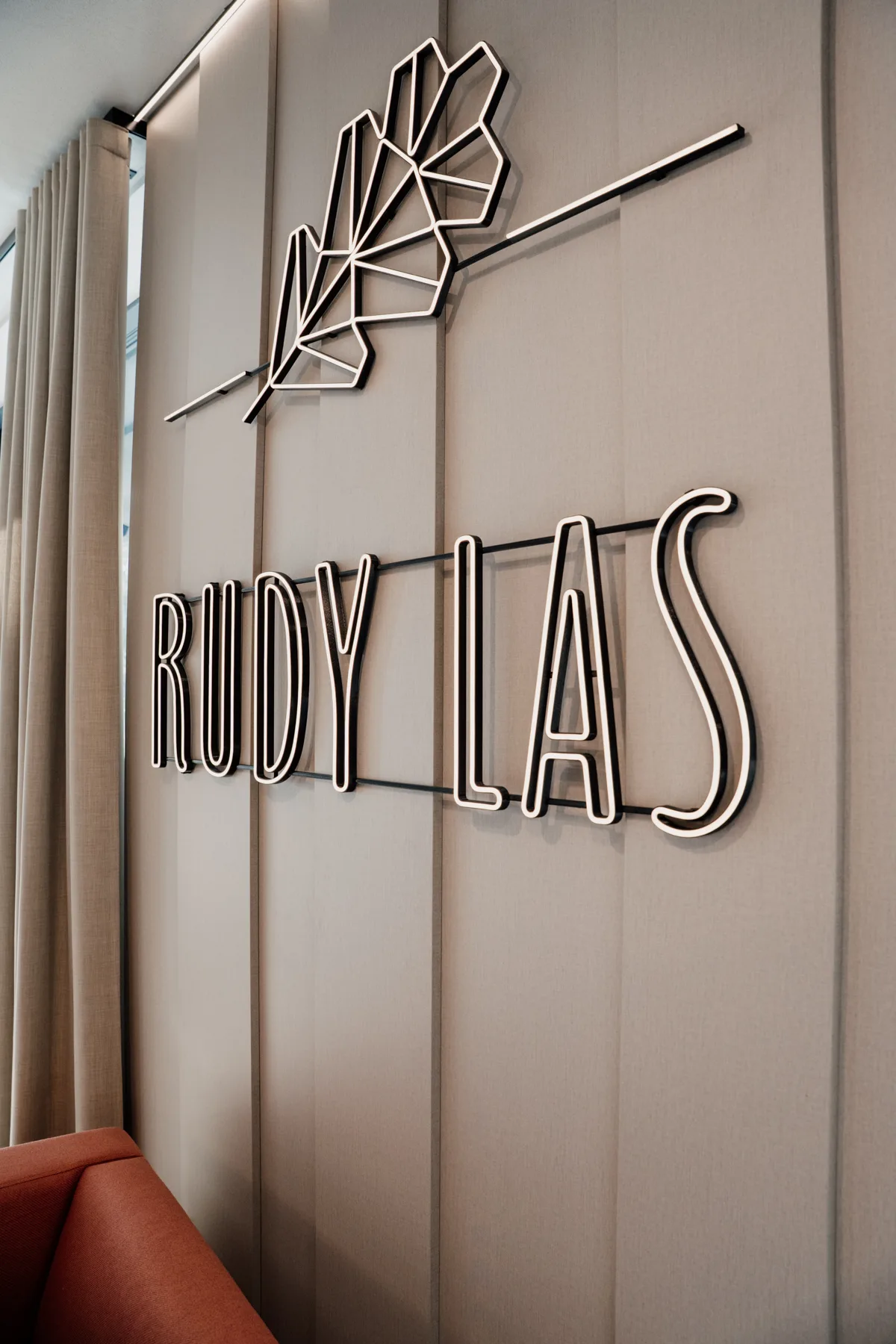 Podświetlany neon z napisem „RUDY LAS” zamontowany na ścianie we wnętrzu restauracji, z dekoracyjnym motywem liścia nad logotypem.