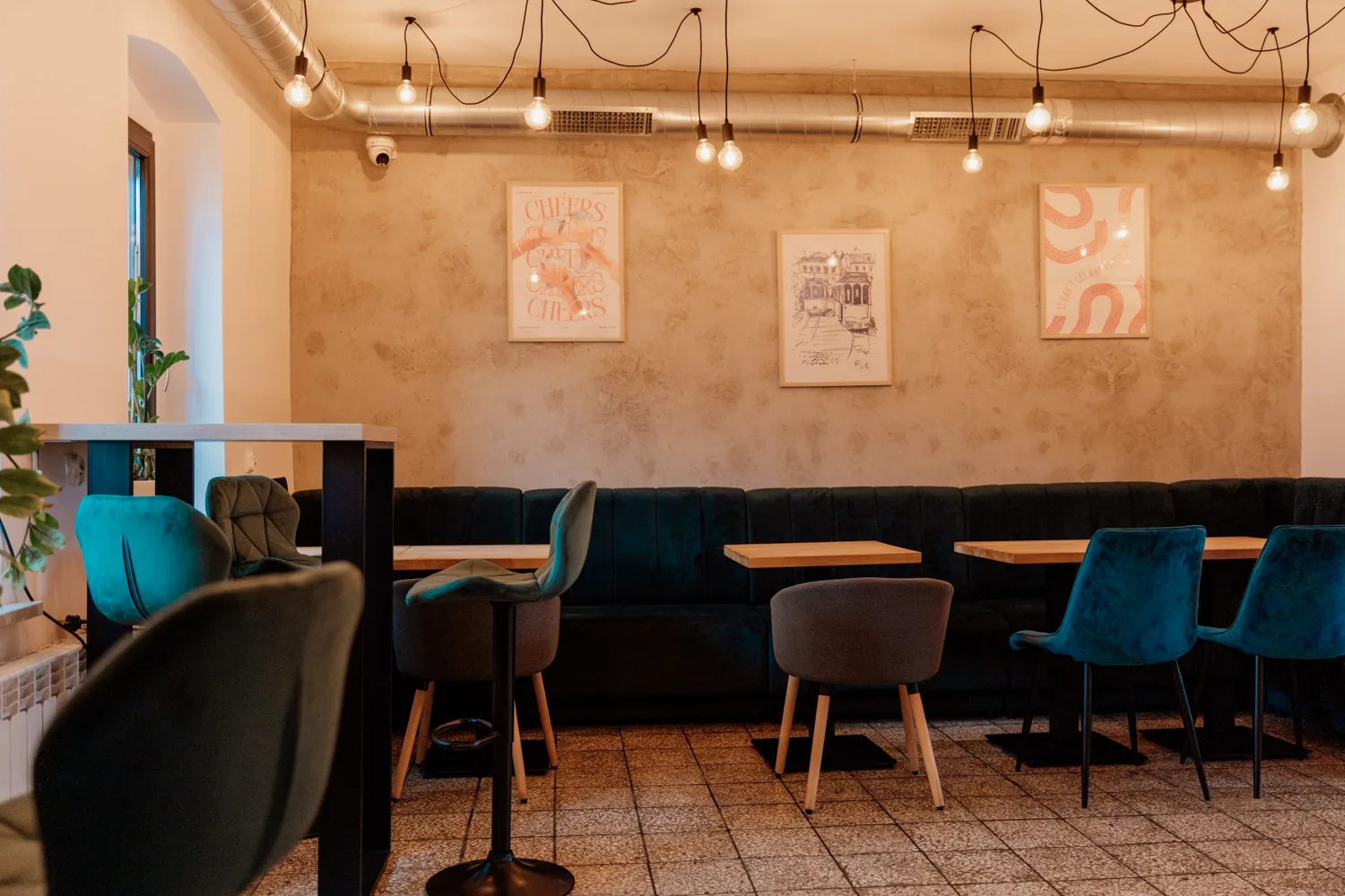 Widok na salę w lokalu gastronomicznym, welurowe fotele i kanapy, drewniane stoliki.