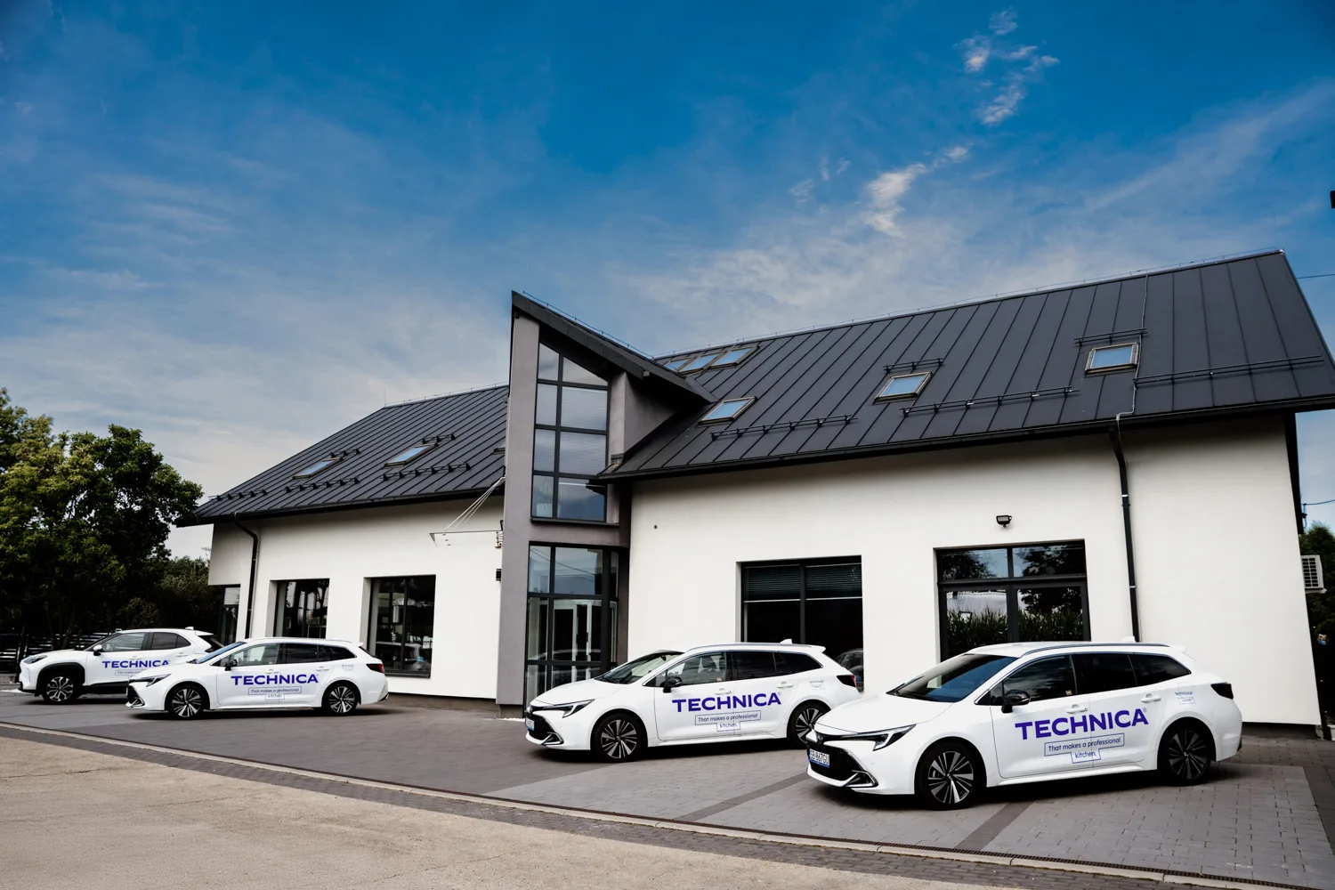 Siedziba firmy Technica – nowoczesny budynek biurowo-showroomowy z zaparkowanymi samochodami firmowymi oznaczonymi logo Technica.