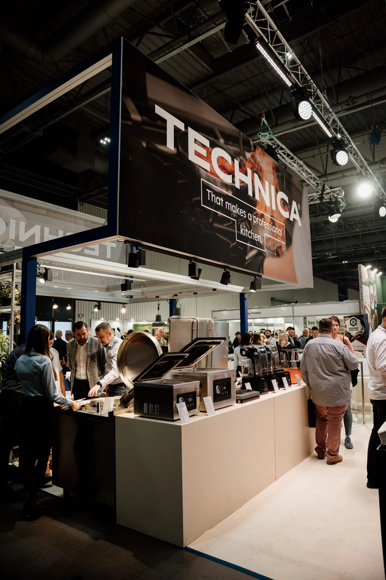 Stoisko marki Technica na targach branży HoReCa, z ekspozycją profesjonalnych urządzeń gastronomicznych i odwiedzającymi zapoznającymi się z ofertą.