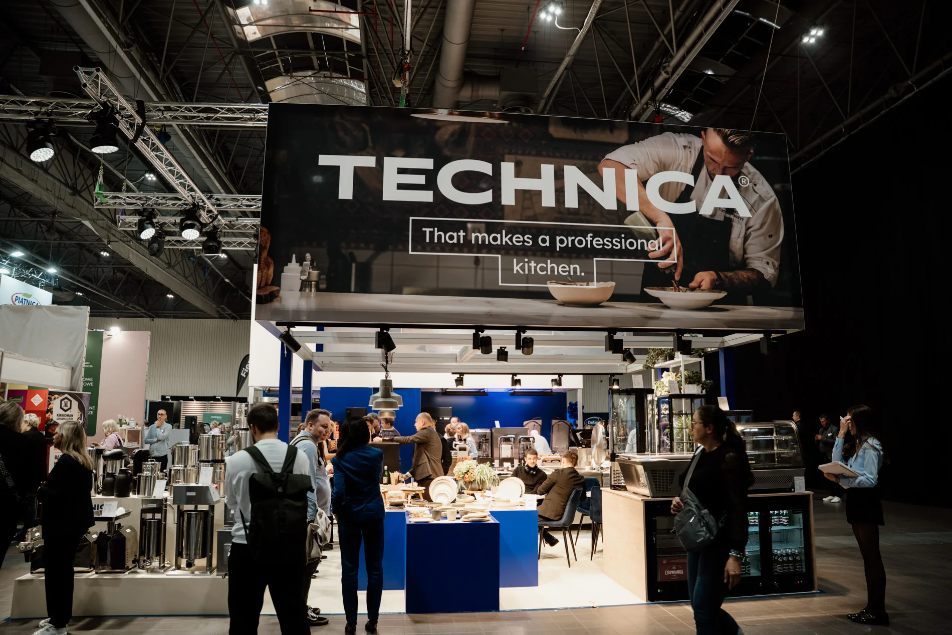 Stoisko marki Technica na targach HoReCa, z dużym banerem „That makes a professional kitchen”, prezentacją profesjonalnego sprzętu gastronomicznego oraz odwiedzającymi.