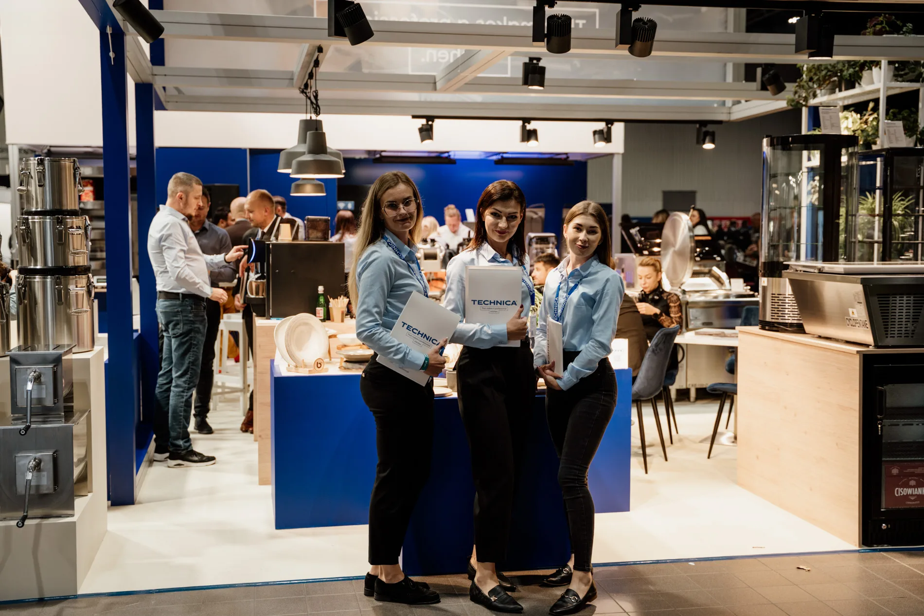 Zespół hostess Technica na stoisku targowym HoReCa, prezentujący ofertę i materiały firmowe w otoczeniu profesjonalnego sprzętu gastronomicznego.