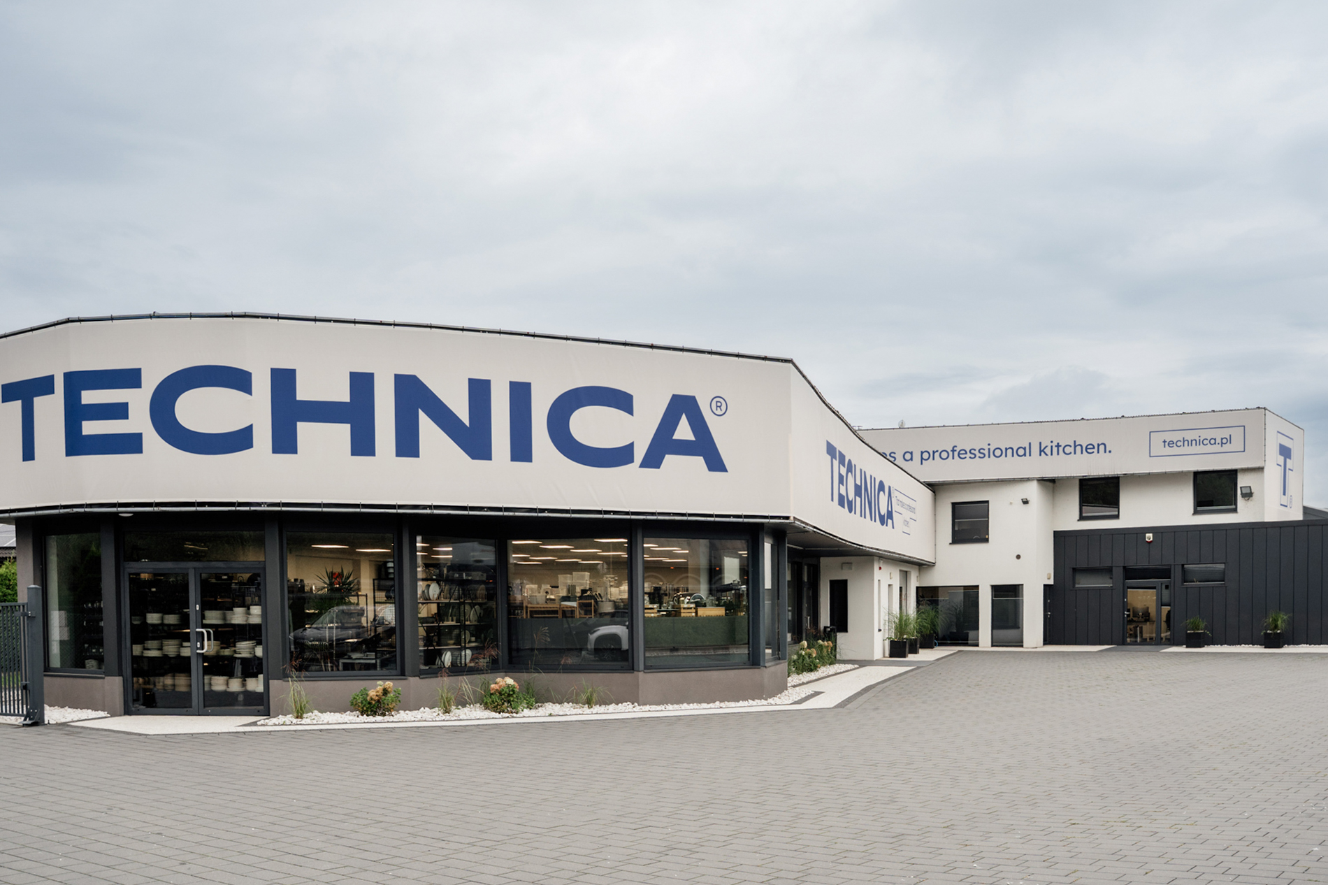 Nowoczesny budynek firmy Technica z dużym logo na elewacji, przeszklonym showroomem i siedzibą firmy oferującej profesjonalne wyposażenie gastronomiczne HoReCa.